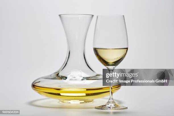 a glass carafe and a glass of white wine on a white surface - carafe stock pictures, royalty-free photos & images