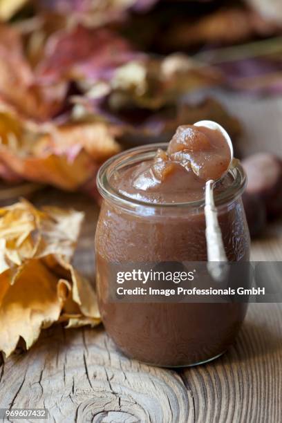 chestnut cream in a jar on a wooden surface with autumnal leaves - chataignes photos et images de collection