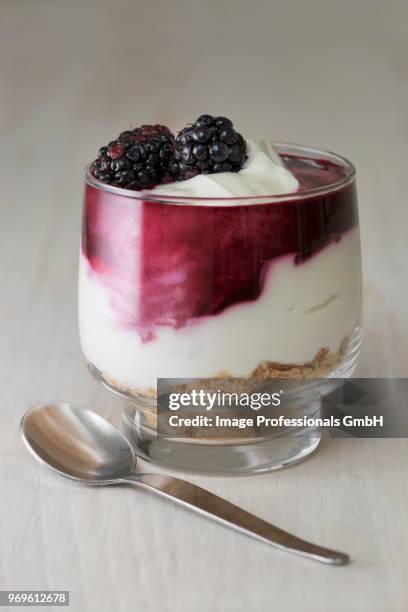 blackberry cheesecake made withcream cheese, cream, blackberry coulis and crushed biscuits served in a glass - süßgebäck teilchen stock-fotos und bilder