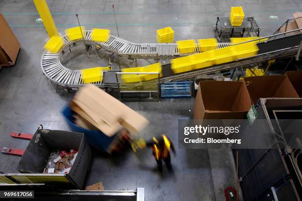 An employee pulls a pallet jack past plastic crates moving along a conveyor at the Amazon.com Inc. Fulfillment center in Robbinsville, New Jersey,...