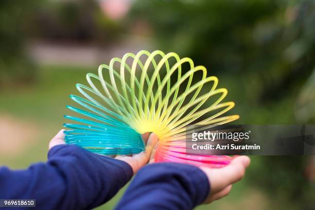 girl playing with rainbow colored wire spiral toy on white background. - molla foto e immagini stock