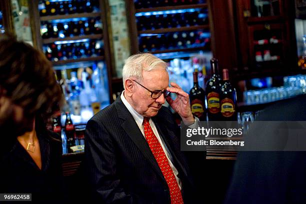 Warren Buffett, chief executive officer of Berkshire Hathaway, adjusts his glasses during a television interview in advance of a charity lunch with a...