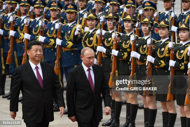 Russia's President Vladimir Putin reviews a military honour guard with Chinese President Xi Jinping during a welcoming ceremony outside the Great...