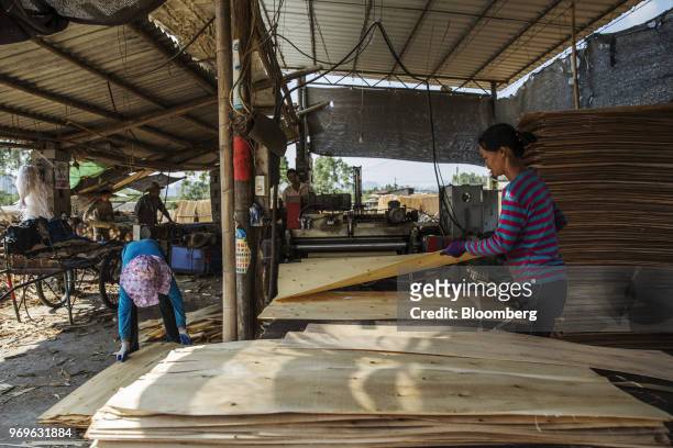 Workers check sheets of eucalyptus wood in a shed at a yard near Liuzhou, Guangxi province, China, on Tuesday, May 23, 2018. China is scheduled to...