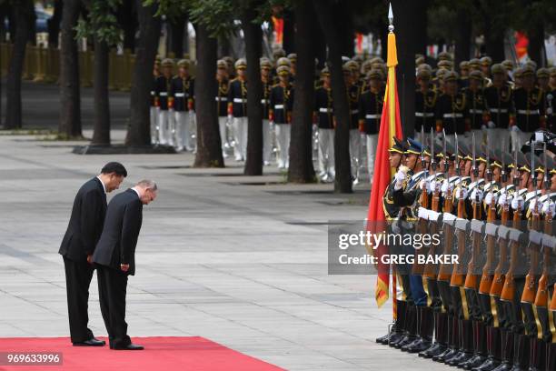 Russia's President Vladimir Putin and Chinese President Xi Jinping bow as they review a military honour guard during a welcoming ceremony outside the...