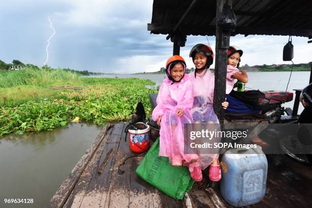 Out of school at the end of the day. Schoolgirls on the small ferry crossing the river on the way back home. Lightning is seen in the background...