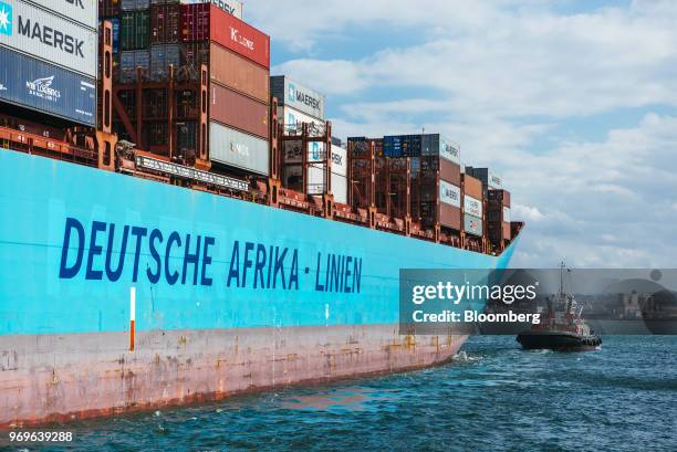 Tug boat navigates the water alongside the cargo ship MV DAL Kalahari, operated by DAL Deutsche Afrika-Linien GmbH & Co KG, as it departs the Port of...