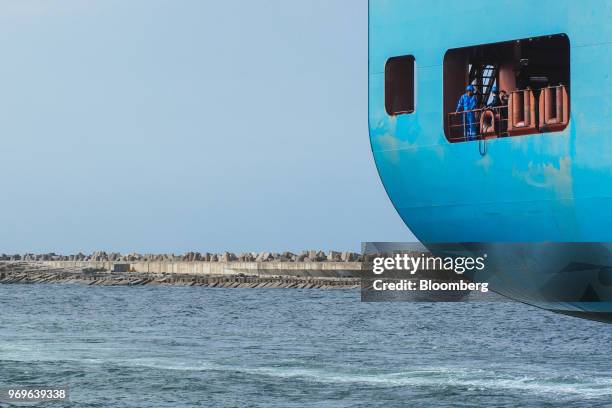 Crew members look out from the rear of the hull of the cargo ship MV DAL Kalahari, operated by DAL Deutsche Afrika-Linien GmbH & Co KG, as it departs...