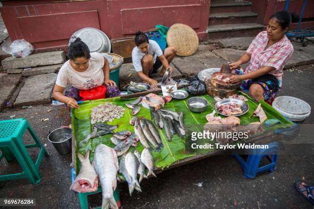 Men and women shop at an outdoor market in Yangon, Myanmar.