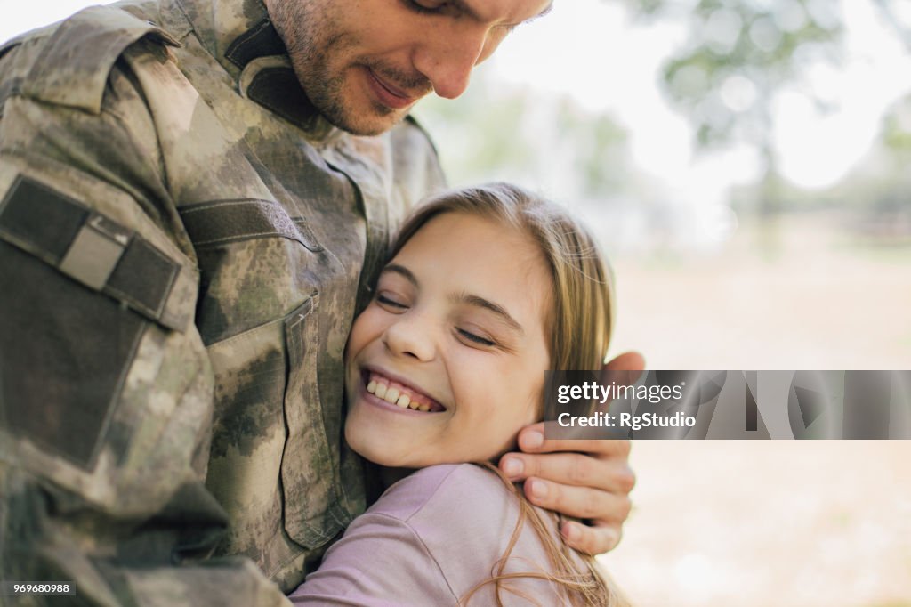 Happy girl hugging a soldier