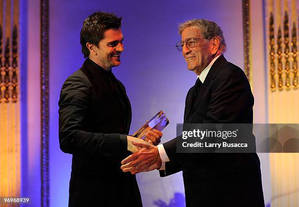 Musician Juanes accepts the AMEE Award in Sound Recordings from singer Tony Bennett at the 2010 AFTRA AMEE Awards at The Grand Ballroom at The Plaza...