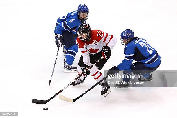 Hayley Wickenheiser of Canada handles the puck against Michelle Karvinen and Jenni Hiirikoski of Finland during the ice hockey women's semifinal game...