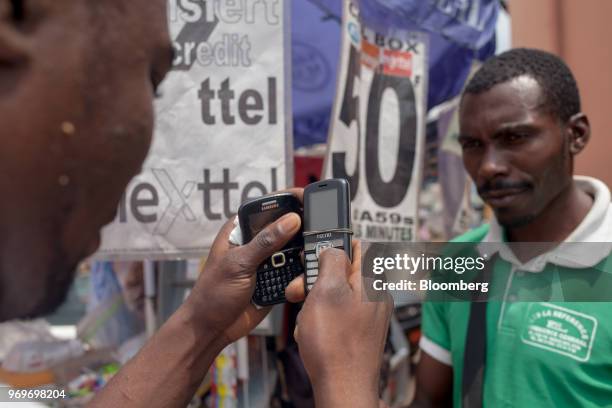 Street vendor enters mobile phone airtime credit to a customers mobile phone at the Nkol Eton market in Yaounde, Cameroon, on Tuesday, June 5, 2018....