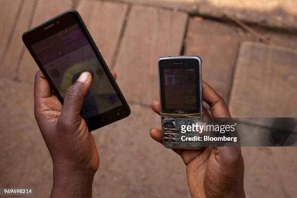 Pedestrian uses two mobile phone handsets simultaneously at the Nkol Eton market in Yaounde, Cameroon, on Tuesday, June 5, 2018. Cameroon adjusted...