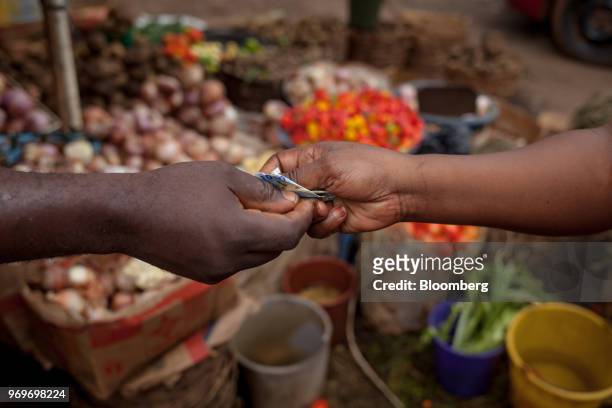 Customer exchanges Central African franc banknotes for fresh produce at a fruit and vegetable kiosk at Nkol Eton market in Yaounde, Cameroon, on...