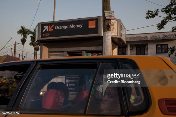 Taxi passes in front of an Orange Money Ltd. Money-transfer kiosk on Nouvelle Route Bastos, in Yaounde, Cameroon, on Tuesday, June 5, 2018. Cameroon...