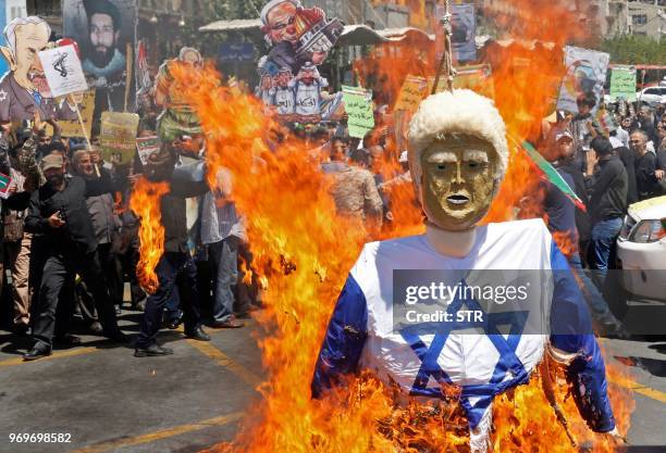 Iranian protestors burn an effigy of US President Donald Trump dressed in an Israeli flag during a rally to mark "Qods day" , an annual day of...