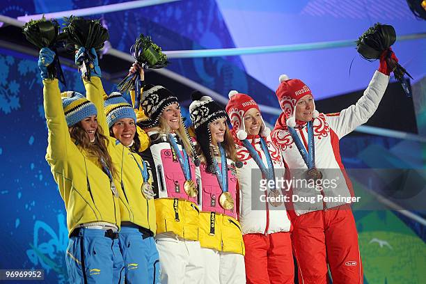 Anna Haag and Charlotte Kalla of Sweden receive the silver medal, Claudia Nystad and Evi Sachenbacher-Stehle of Germany receive the gold medal and...