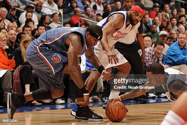 Stephen Jackson of the Charlotte Bobcats reaches for a loose ball against Baron Davis and Rasual Butler of the Los Angeles Clippers at Staples Center...