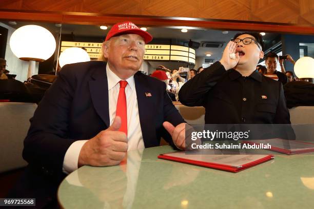 Kim Jong-un impersonator, Howard X and Donald Trump impersonator, Dennis Alan looks to order for drinks at Merlion Park on June 8, 2018 in Singapore....