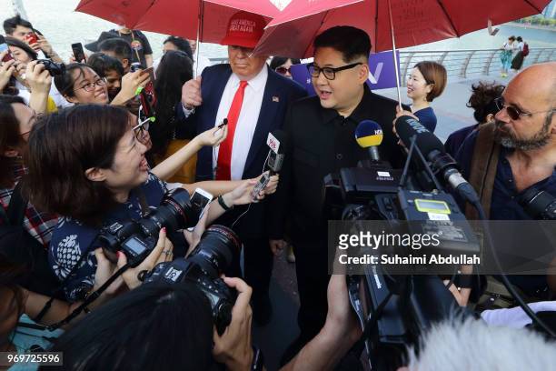 Kim Jong-un impersonator, Howard X and Donald Trump impersonator, Dennis Alan speaks to the media at Merlion Park on June 8, 2018 in Singapore. The...