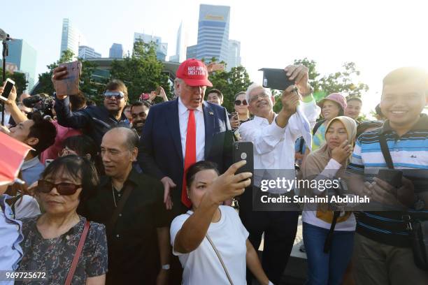 Tourists pose for photo with Donald Trump impersonator, Dennis Alan at Merlion Park on June 8, 2018 in Singapore. The White House confirmed on...