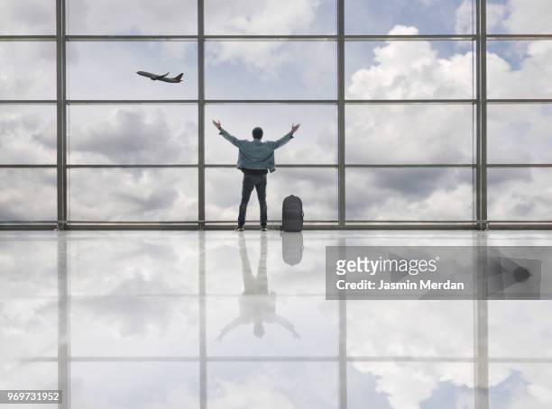 man with arms up on airport looking at airplane flying - jasmin merdan stock-fotos und bilder