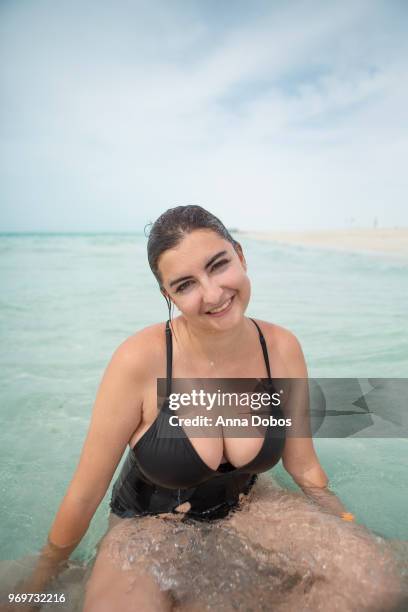 woman sits in water looks at camera and smiles - emirati enjoy stock-fotos und bilder