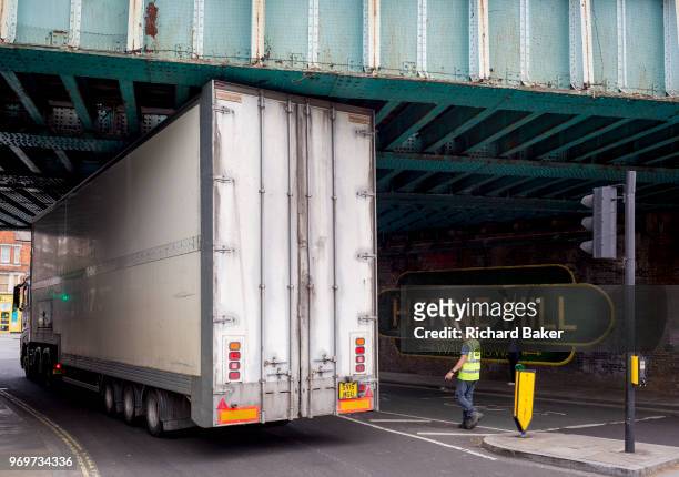 High-sided HGV lorry squeezes under the railway bridge over the A215 at Herne Hill, on 7th June 2018, in south London, England.