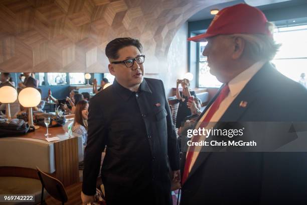 Kim Jong Un impersonator, Howard X and Donald Trump impersonator Dennis Alan chat in a restaurant during a visit to the famous Merlion Park on June...