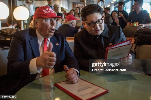 Kim Jong Un impersonator, Howard X and Donald Trump impersonator Dennis Alan sit in a restaurant during a visit to the famous Merlion Park on June 8,...