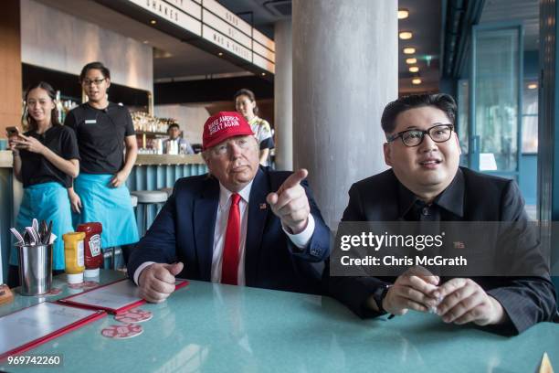 Kim Jong Un impersonator, Howard X and Donald Trump impersonator Dennis Alan sit in a restaurant during a visit to the famous Merlion Park on June 8,...