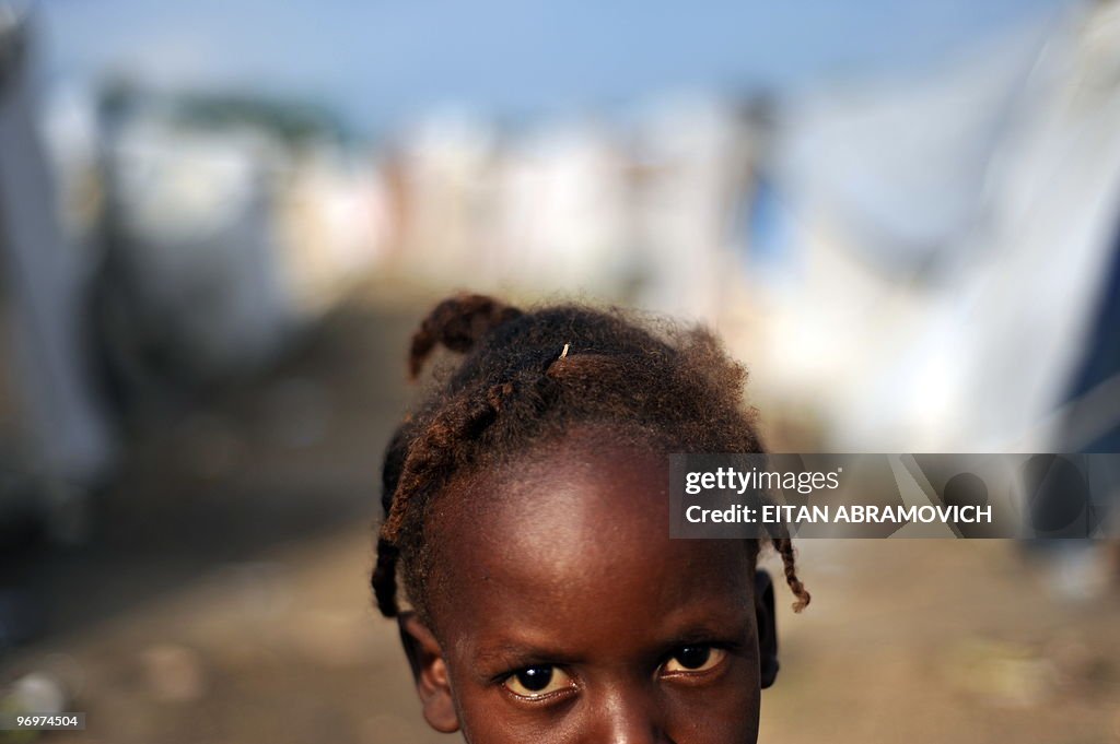 A Hatian girl stands amid tents in a cam