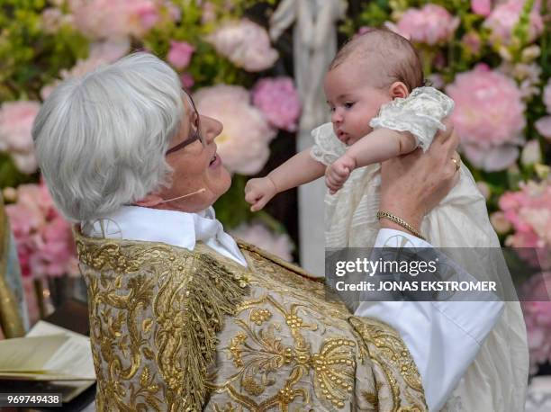 Officiant Archbishop Antje Jackelen holds princess Adrienne of Sweden during princess Adrienne's christening ceremony in Drottningholm Palace Chapel...