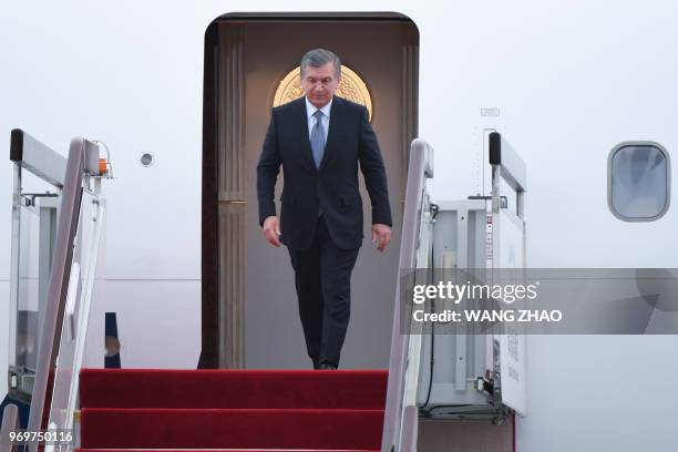 Uzbekistan President Shavkat Mirziyoyev walks out from the airplane upon his arrival at Qingdao Liuting International Airport in Qingdao, China's...