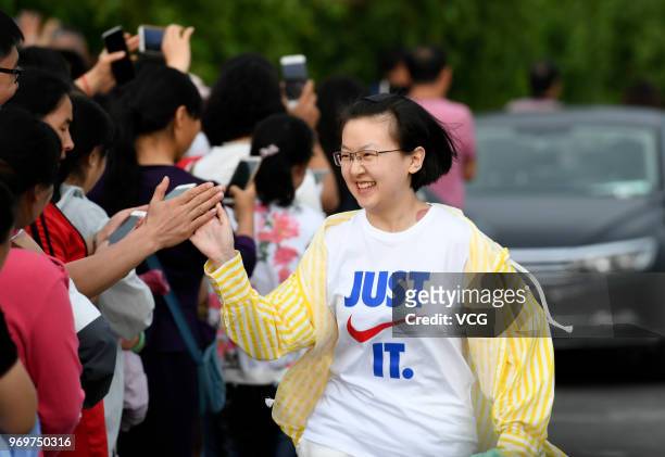 Candidate wearing Nike sportswear gives high-five to parents before entering an exam site for the National College Entrance Examination as the...