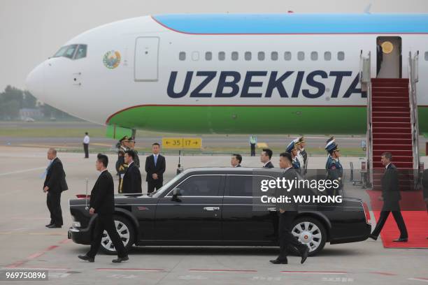 Chinese guard personnel guards follow the car of Uzbekistan President Shavkat Mirziyoyev after he arrived at Qingdao Liuting International Airport...