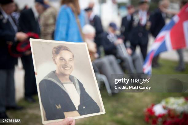 Woman holds a wartime photograph of Royal Navy veteran Patrick Thomas at a memorial service close to the beach at Lion-sur-Mer where his landing...