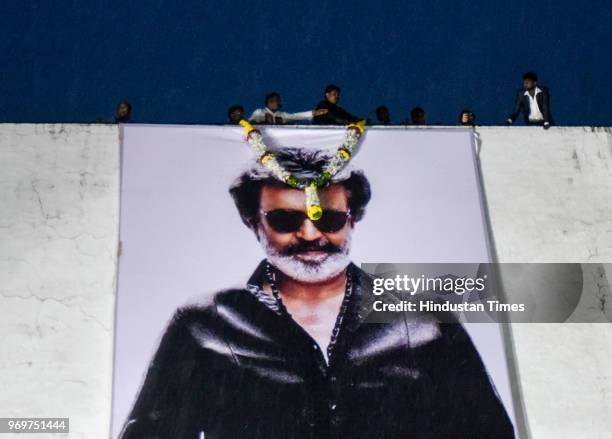 Indian fans pours water on a hoarding of actor Rajinikanth in front of a movie theatre on the first day of release of his new film Kaala at Carnival...