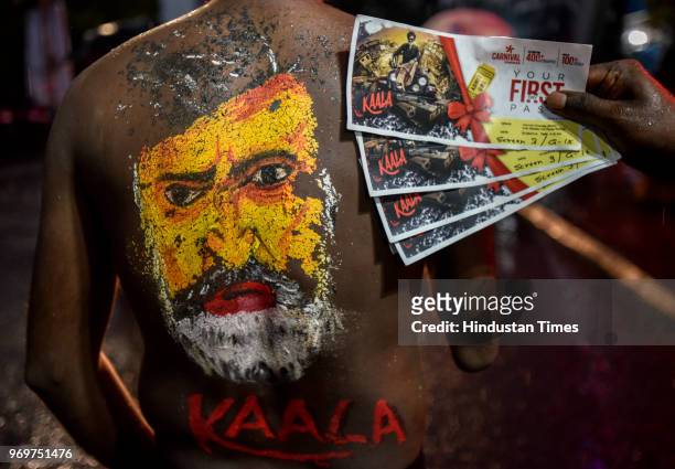 Fan display tickets of first show in front of Indian Bollywood star Rajinikanth body paint with a portrait of the actor on the first day of release...