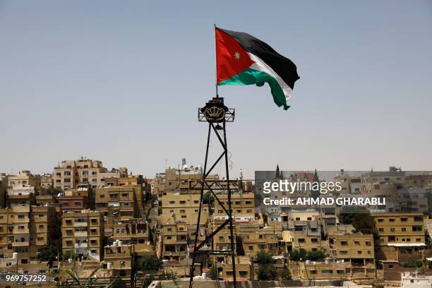 General view taken from Jabal al-Qala district shows a Jordanian flag fluttering above the Jordanian capital Amman on June 8, 2018. - Jordan's...
