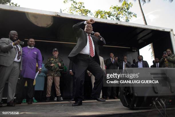 Former South African President Jacob Zuma sings and dances on stage after delivering a speech during a rally in his support outside the High Court,...