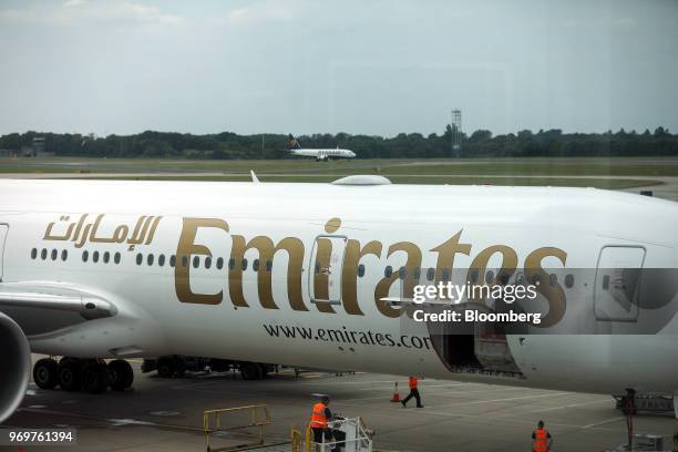 Members of the ground crew access the cargo hold of a Boeing Co. 777-300ER passenger jetliner, operated by Emirates Airline, as a passenger aircraft,...