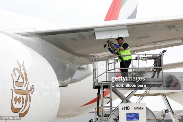 Member of the ground crew connects a fuel supply pipe to a Boeing Co. 777-300ER passenger jetliner, operated by Emirates Airline, at London Stansted...