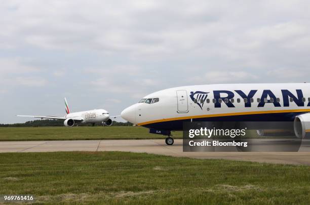 Passenger aircraft, operated Ryanair Holdings Plc, taxis on the tarmac near a Boeing Co. 777-300ER passenger jetliner, operated by Emirates Airline,...