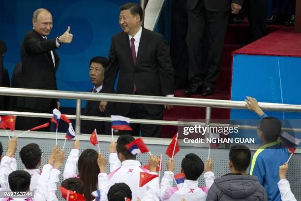 Russian President Vladimir Putin gives a thumbs up as Chinese President Xi Jinping reacts to cheers from spectators at the friendly match between...