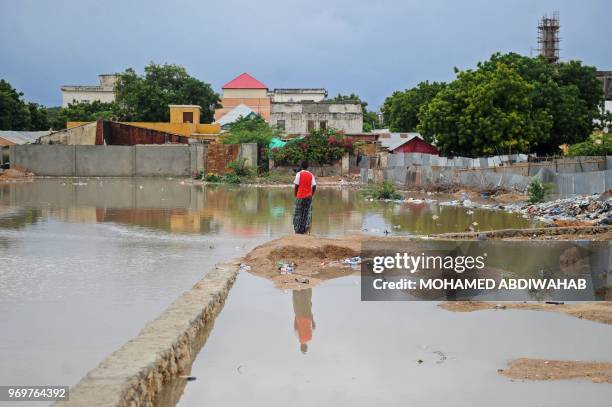 Man stands next to a flooded street on June 8, 2018 in Mogadishu, after heavy rain storms hit the capital overnight.