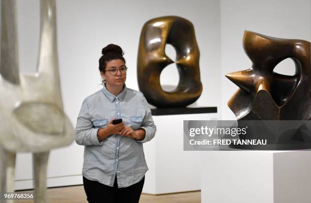 Woman passes by bronze sculptures called "Working model for oval with points" and "Working model for spindle piece" by late British artist Henry...