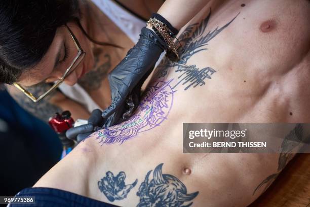 Tattoo artist Sick Rose tattoes a Christ head with thorn crown on her client Gaetan during the International Tattoo Convention in Dortmund, western...