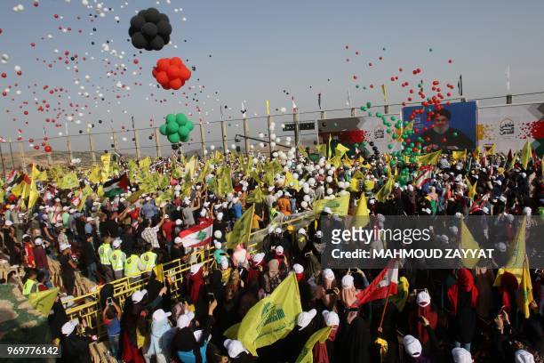 People carry flags of the Lebanese Shiite Muslim Hezbollah movement and national flags during commemorations marking al-Quds day in the village of...